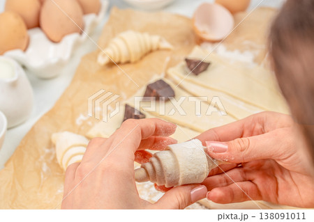 Hands shaping chocolate croissant from puff pastry dough, close-up bakery preparation process Hands shaping chocolate croissant from puff pastry dough, close-up bakery preparation process 138091011