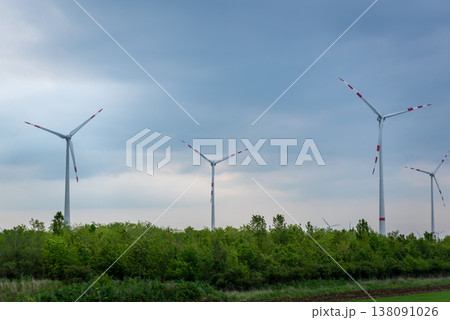Wind turbines over green treeline Wind turbines over green treeline 138091026