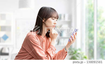 スマートフォンを見て考えごとをする女性・ビジネスウーマン 138091581