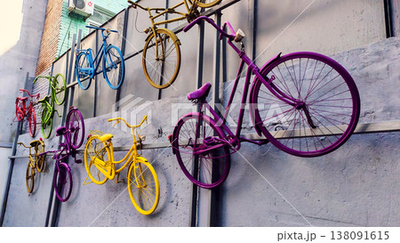 Colorful vintage bicycles mounted on an urban wall as creative street decoration. The vibrant installation reflects urban art, city culture and playful outdoor design. Colorful vintage bicycles mounted on an urban wall as creative street decoration. The vibrant installation reflects urban art, city culture and playful outdoor design. 138091615