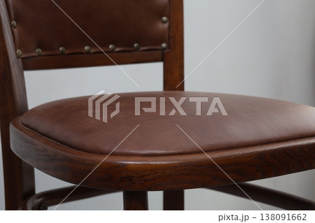 Elegant wooden chair with rich brown leather seat in a cozy indoor setting brings warmth and style to any room decor Elegant wooden chair with rich brown leather seat in a cozy indoor setting brings warmth and style to any room decor 138091662
