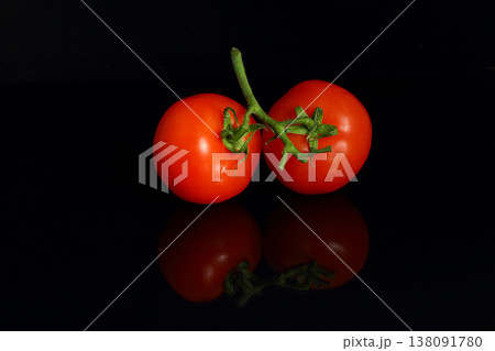Two tomatoes isolated on black background with stem, leaf and water droplets. Two tomatoes isolated on black background with stem, leaf and water droplets. 138091780