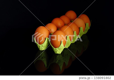 Chicken eggs in a cardboard container for the storage and transportation of chicken eggs isolated on black background 138091802