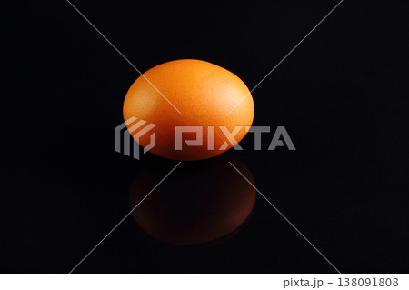 one yellow chicken egg on a black background 138091808