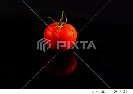 Red mini tomato on black reflective studio background. Isolated black shiny mirror mirrored background for every concept. 138091810