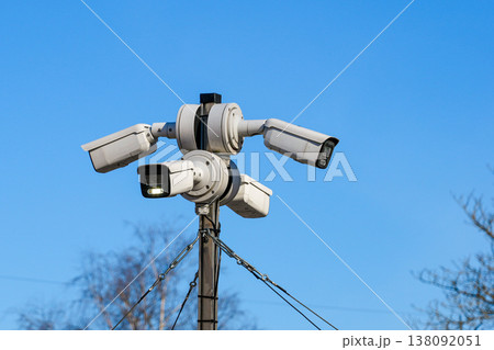 Multi direction CCTV surveillance cameras mounted on pole monitoring area under clear blue sky 138092051