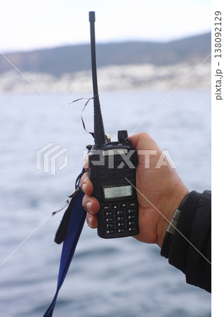 A man holds a portable walkie-talkie in his hand to communicate with other people in winter. The method of communication for winter fishing. 138092129