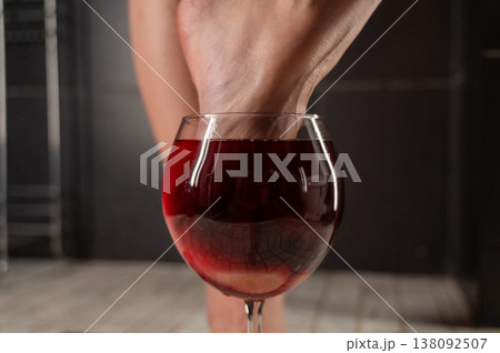 Foot fetish. A woman dips her toes in a glass of red wine. Foot fetish. A woman dips her toes in a glass of red wine. 138092507