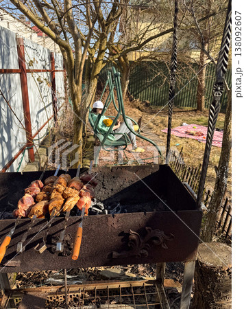 Grilling meat skewers over charcoal in sunny backyard 138092607
