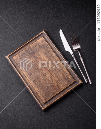An empty wooden cutting board with cutlery on a kitchen counter. A wooden cutting board 138092989