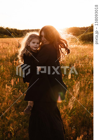 Mother Embraces Daughter. Gentle Silhouette Of Mother Shielding Daughter In Field Glow 138093018