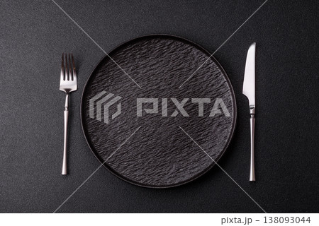 An empty round ceramic plate, knife, and fork as a dining table setting. An empty plate 138093044