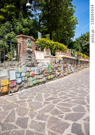 Muretto di alassio, a famous landmark in liguria, italy, displaying numerous signed ceramic tiles from celebrities and a bronze statue along the stone wall, creating a cultural attraction 138093934
