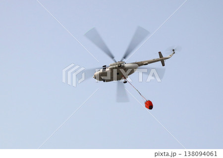Fire fighting helicopter with water bucket on the background of a gloomy sky Fire fighting helicopter with water bucket on the background of a gloomy sky 138094061
