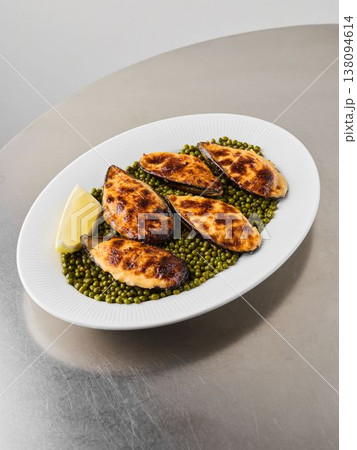 Satisfying baked mollusks accompanied by fresh green peas and lemon segment Satisfying baked mollusks accompanied by fresh green peas and lemon segment 138094614