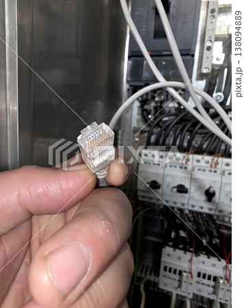 Installing a Network in a Tech Space With an Ethernet Connector in Hand Installing a Network in a Tech Space With an Ethernet Connector in Hand 138094889