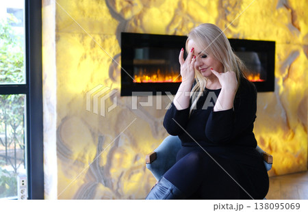 Cozy glamour mature woman leaning on table near fireplace black dress indoor fashion lifestyle confident pose elegant atmosphere Cozy glamour mature woman leaning on table near fireplace black dress indoor fashion lifestyle confident pose elegant atmosphere 138095069