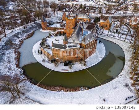 Detailed aerial view of Huis Bergh Castle in winter. Historical medieval brick fortress surrounded by a frozen circular moat and snow covered grounds in a picturesque European town landscape. Detailed aerial view of Huis Bergh Castle in winter. Historical medieval brick fortress surrounded by a frozen circular moat and snow covered grounds in a picturesque European town landscape. 138097148