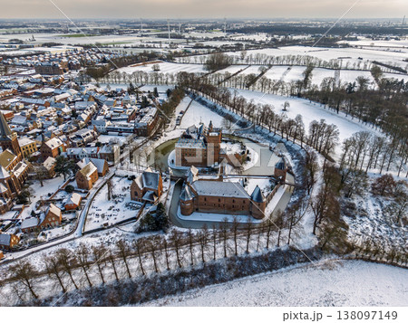 Panoramic aerial view of Huis Bergh castle and the surrounding town in winter. A stunning medieval fortress with a moat, surrounded by snow covered fields, historic houses, and wind turbines. Panoramic aerial view of Huis Bergh castle and the surrounding town in winter. A stunning medieval fortress with a moat, surrounded by snow covered fields, historic houses, and wind turbines. 138097149