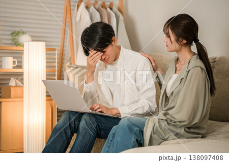 リビングのソファでパソコンで仕事をする夫を心配そうに見つめる妻（残業,持ち帰り残業,隠れ残業） 138097408