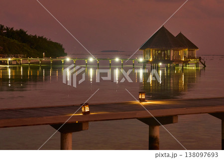 The night landscape of the Maldives island pier with night lighting against the pink sky, Magical pink sky at dusk on Maldives islands, reflection on the water in beach, no people  138097693