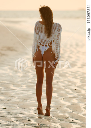 A beautiful tanned girl in a swimsuit stands along a white beach at sunset in the Maldives, she is happy, posing for a photographer A beautiful tanned girl in a swimsuit stands along a white beach at sunset in the Maldives, she is happy, posing for a photographer 138097884