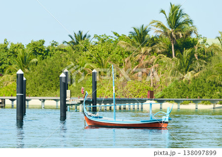 Classic Maldives island landscape on a sunny day, moored boat, coastal luxury resort buildings, azure water, white sand, palm trees on the shore Classic Maldives island landscape on a sunny day, moored boat, coastal luxury resort buildings, azure water, white sand, palm trees on the shore 138097899