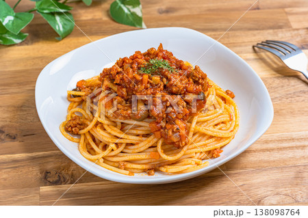 ミートソースパスタ 白い皿に盛り付けたボロネーゼ 木目テーブルの洋食イメージ 138098764