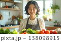 明るいモダンなキッチンでエプロン姿で料理をする笑顔の日本人母親の自然なスナップ写真 138098915
