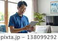 明るいリビングでタブレット端末を操作する笑顔の日本人男性介護士 138099292