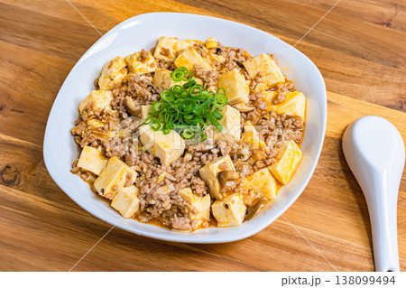 麻婆豆腐 白い皿に盛り付けた中華料理 木目テーブルの家庭料理 麻婆豆腐 白い皿に盛り付けた中華料理 木目テーブルの家庭料理 138099494