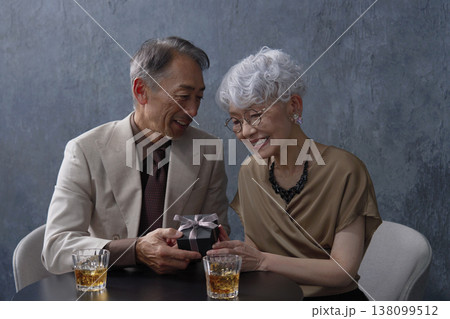 プレゼントをシニアの女性に渡す男性　黒背景 138099512