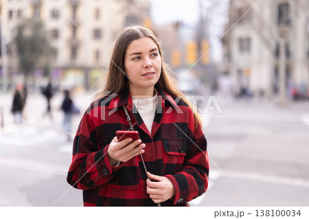Girl traveler walks through tourist area of European city with phone 138100034