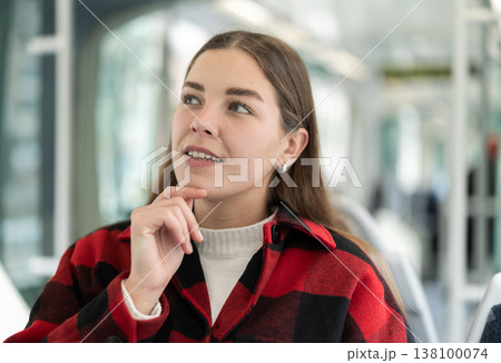 Young woman sitting in tram and looking away Young woman sitting in tram and looking away 138100074