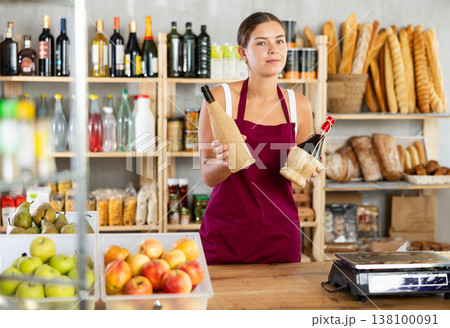 Young female seller offering wine in grocery store Young female seller offering wine in grocery store 138100091