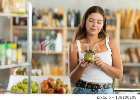 Young woman choosing green peas in grocery store 138100109
