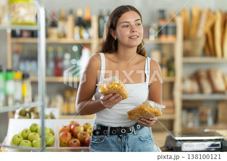 In grocery supermarket, female shopper chooses corn flakes for breakfast 138100121