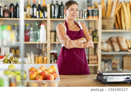 Young woman seller at counter in grocery store 138100127