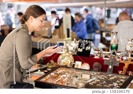 Young woman looking at retro ashtray at flea market Young woman looking at retro ashtray at flea market 138100170