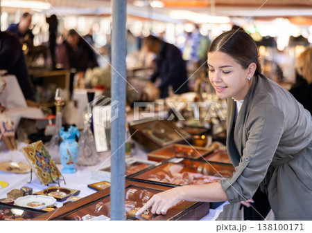Young woman chooses vintage jewelry at flea market 138100171