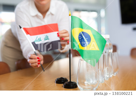 Little flag of Brazil on table and flag of Iraq put next to it by young woman 138100221
