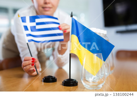 Unrecognizable girl sets midget flags of Ukraine and Greece before international negotiations Unrecognizable girl sets midget flags of Ukraine and Greece before international negotiations 138100244