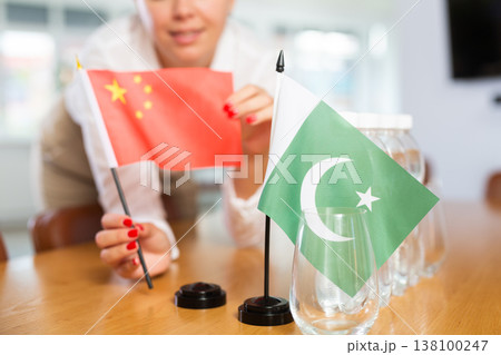 Little flag of Pakistan on table and flag of China put next to it by young woman 138100247