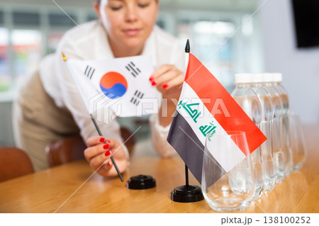 Employee of delegation prepares negotiating table - sets up flag of South Korea and Iraq Employee of delegation prepares negotiating table - sets up flag of South Korea and Iraq 138100252