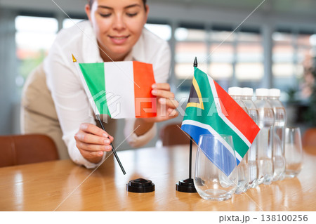 Little flag of South Africa on table and flag of Italy put next to it by young woman 138100256