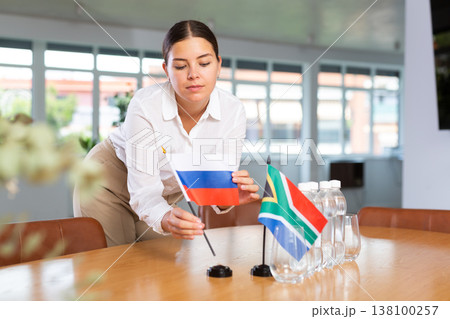 Positive young woman putting little flag of Russia on table next to the flag of South Africa 138100257