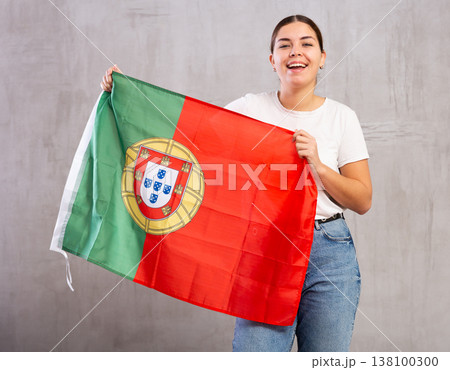 Happy girl stands with flag of Portugal. Isolated on gray background 138100300