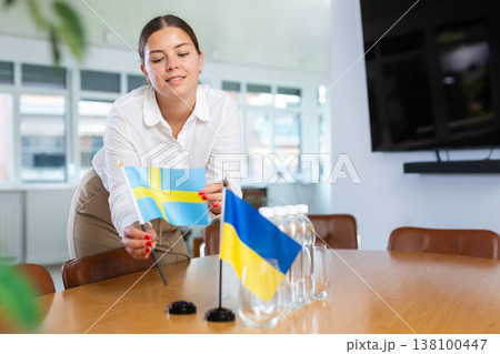 Businesswoman setting flags of Ukraine and Sweden on negotiating table 138100447