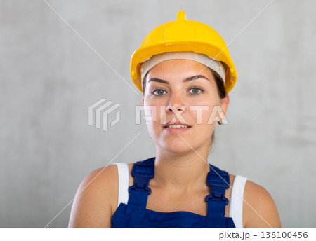 Happy female worker in work clothes and hardhat standing proudly and smiling Happy female worker in work clothes and hardhat standing proudly and smiling 138100456