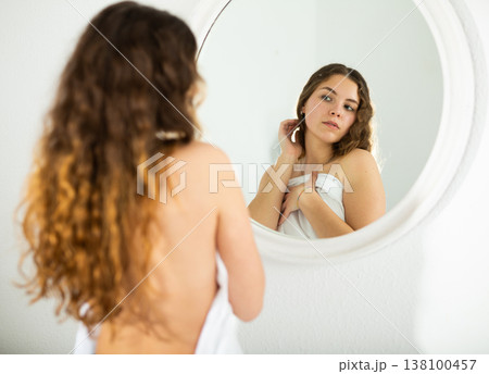 Seminude brown-haired young woman looking at mirror 138100457